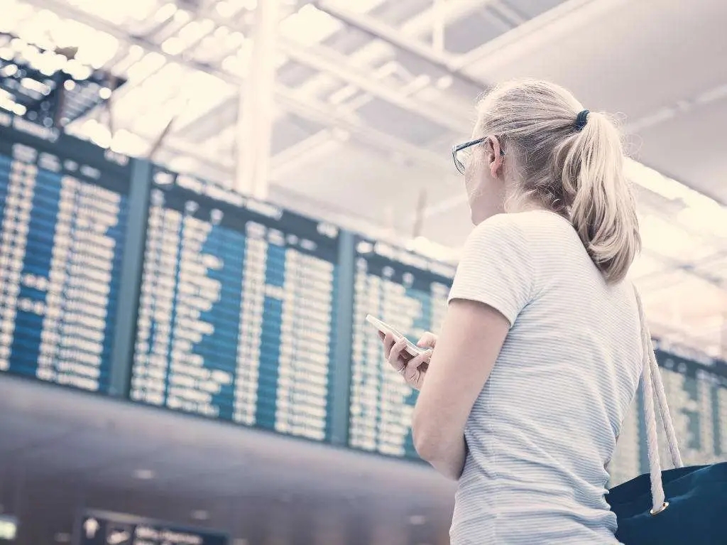 woman looking at airport departures board