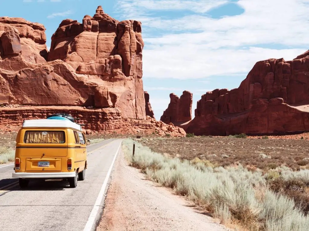 yellow van driving on road in the desert.