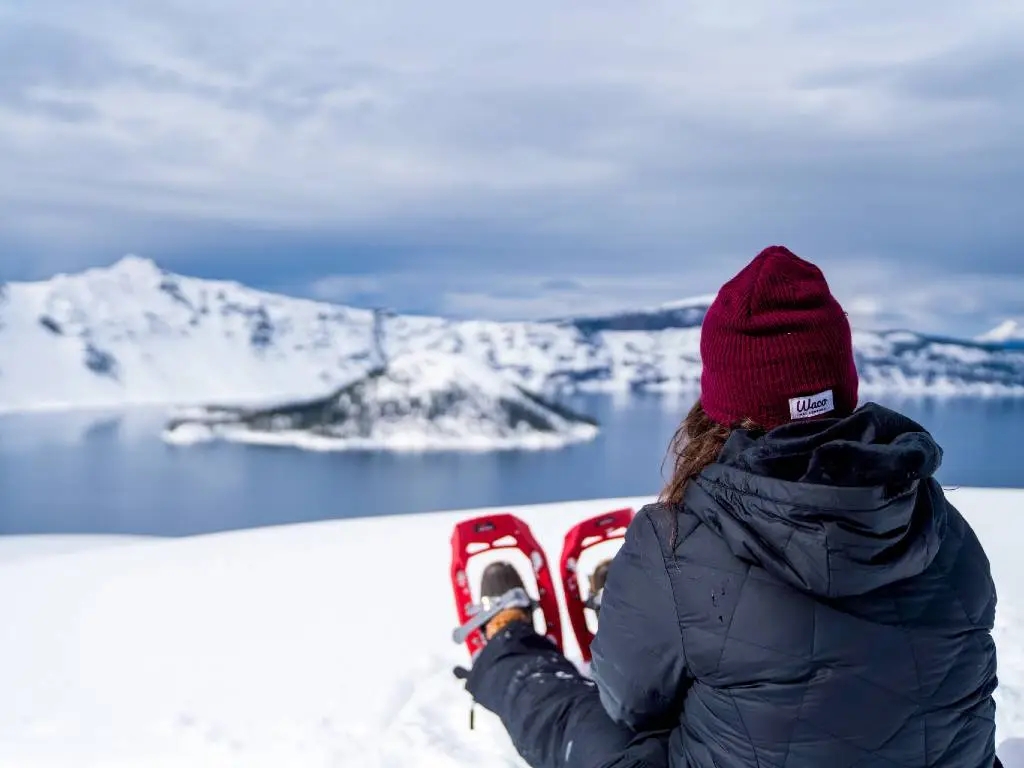 woman snowshoeing above crater lake.