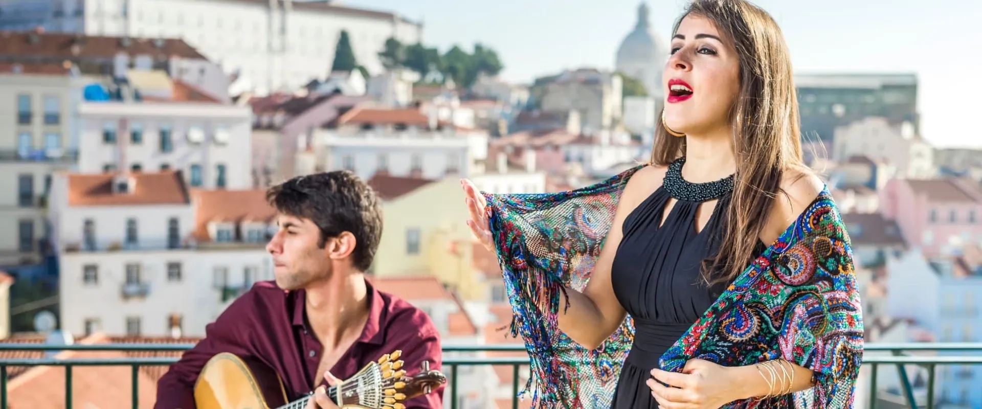 A woman sings fado and a man plays the guitarra on a rooftop in Lisbon